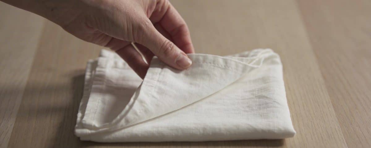 Main de femme pliant serviette blanche sur table