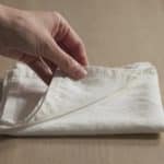 Main de femme pliant serviette blanche sur table