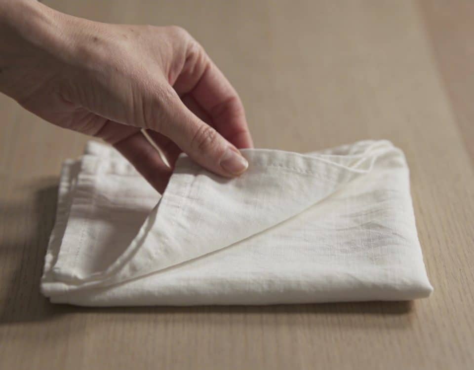 Main de femme pliant serviette blanche sur table