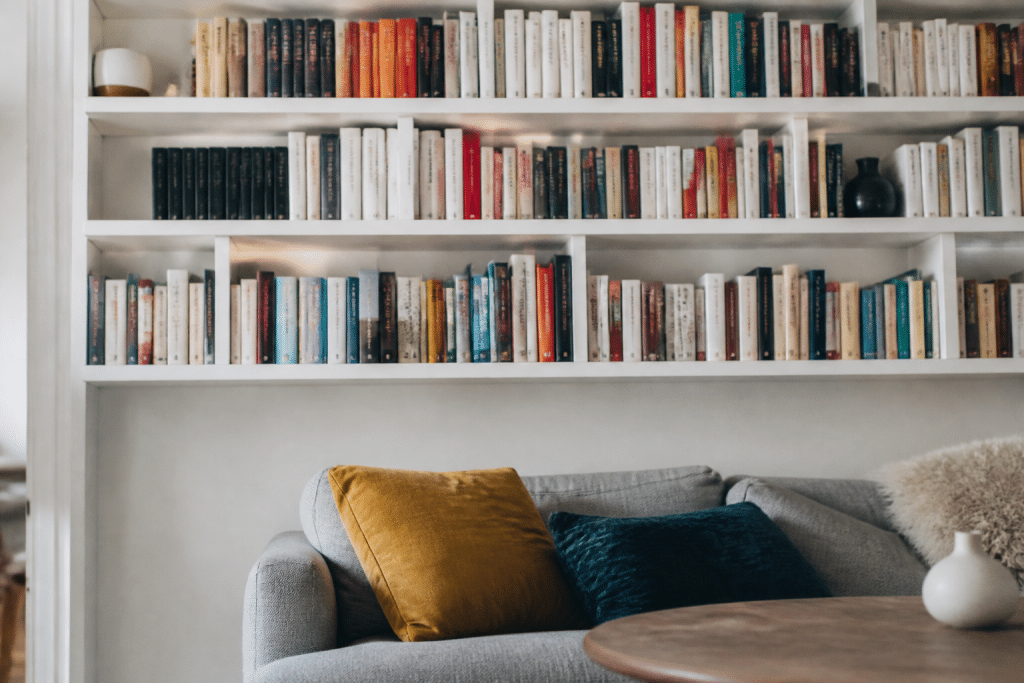 Etageres murales blanches remplies de livres colores dans salon