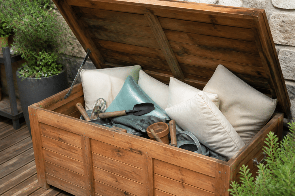 Coffre bois ouvert rempli coussins terrasse outils jardinage
