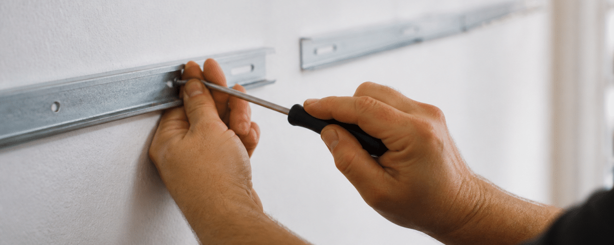 Mains fixant supports metalliques horizontalement sur mur blanc