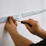 Mains fixant supports metalliques horizontalement sur mur blanc