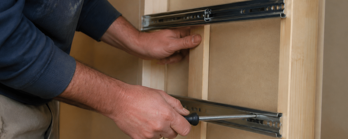 Mains installant rails metalliques sur cadre bois placard