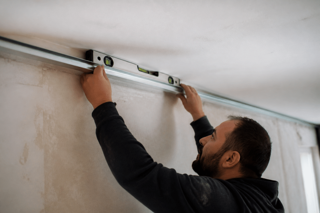 Ouvrier fixe rail metallique plafond niveau bulle