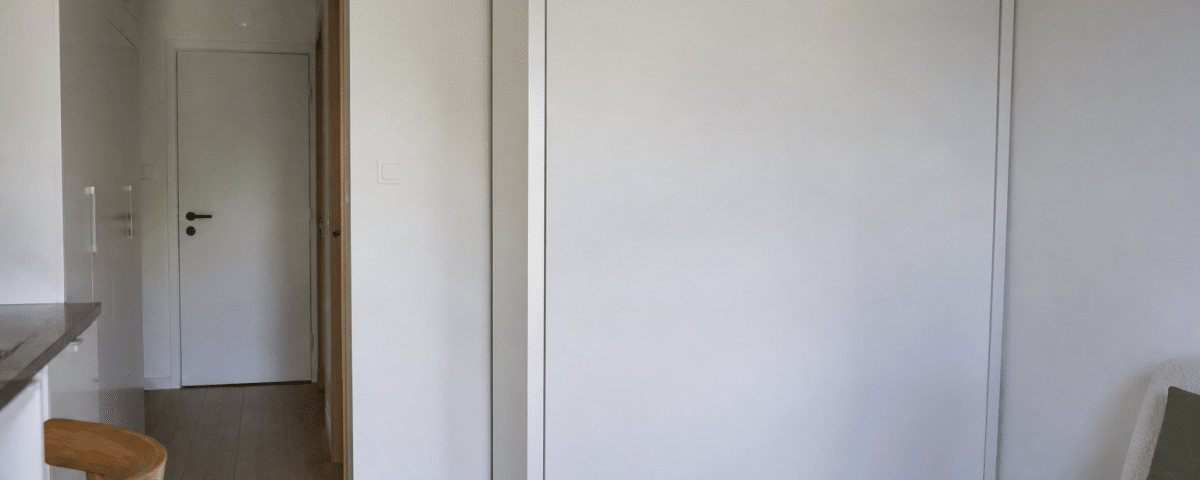 Lit escamotable replié contre mur blanc studio compact