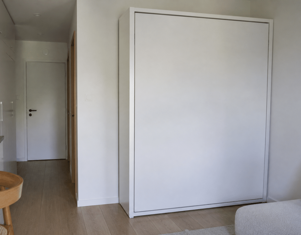 Lit escamotable replié contre mur blanc studio compact
