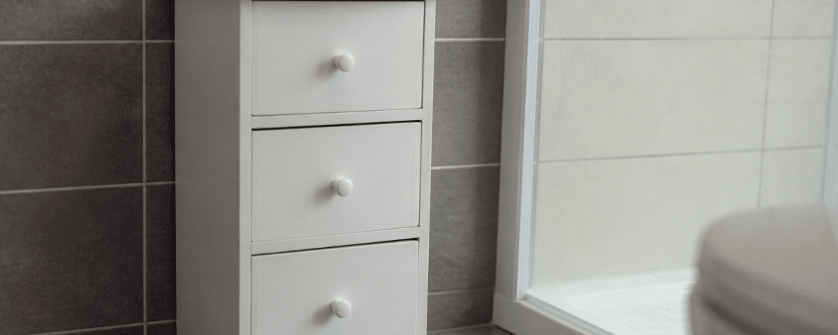 Petit meuble blanc posé contre carrelage salle bain