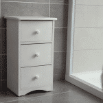 Petit meuble blanc posé contre carrelage salle bain