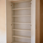 Placard ouvert avec plusieurs etageres blanches installees verticalement