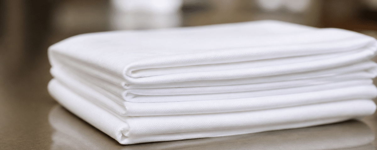 Mains pliant serviette blanche empilée sur surface plane