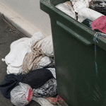 Vetements chiffonnes tombes dans bac poubelle ouvert