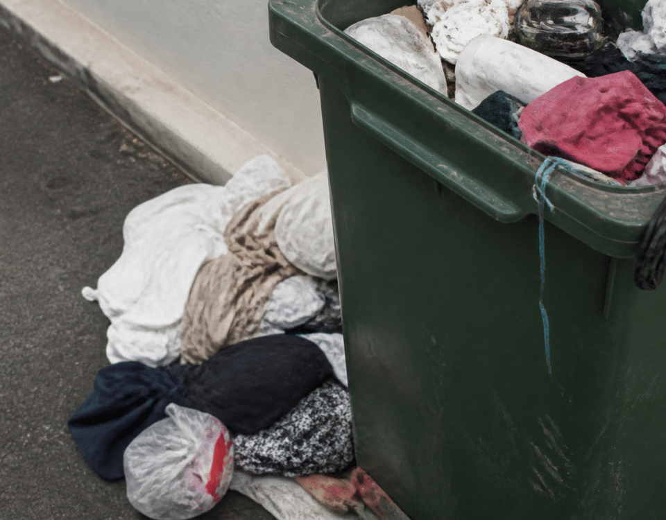Vetements chiffonnes tombes dans bac poubelle ouvert