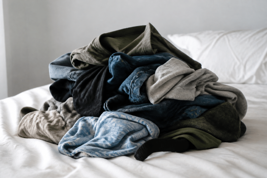 Pile de vêtements usés sur lit blanc